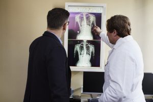 doctor-pointing-x-ray-result-beside-man-wearing-black-suit