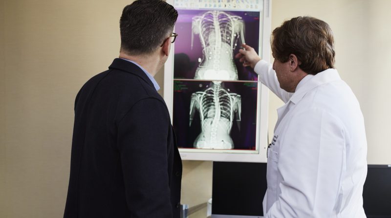 doctor-pointing-x-ray-result-beside-man-wearing-black-suit